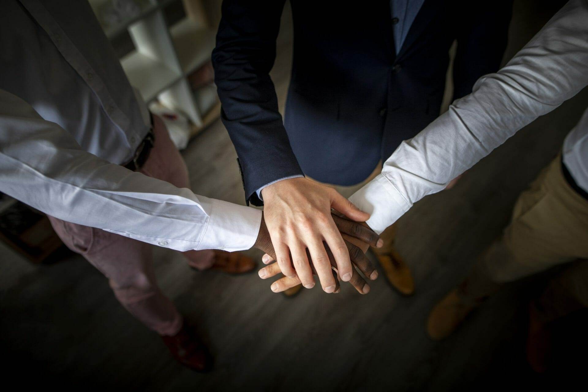 business teamwork joining hands together scaled